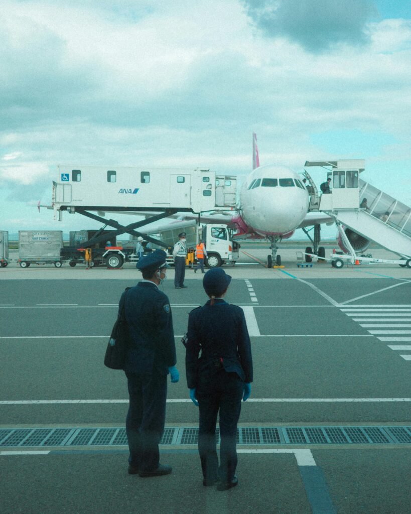 pexels photo 19567702 19567702 Two crew members approach a parked airplane at an airport, with a jet bridge connected.