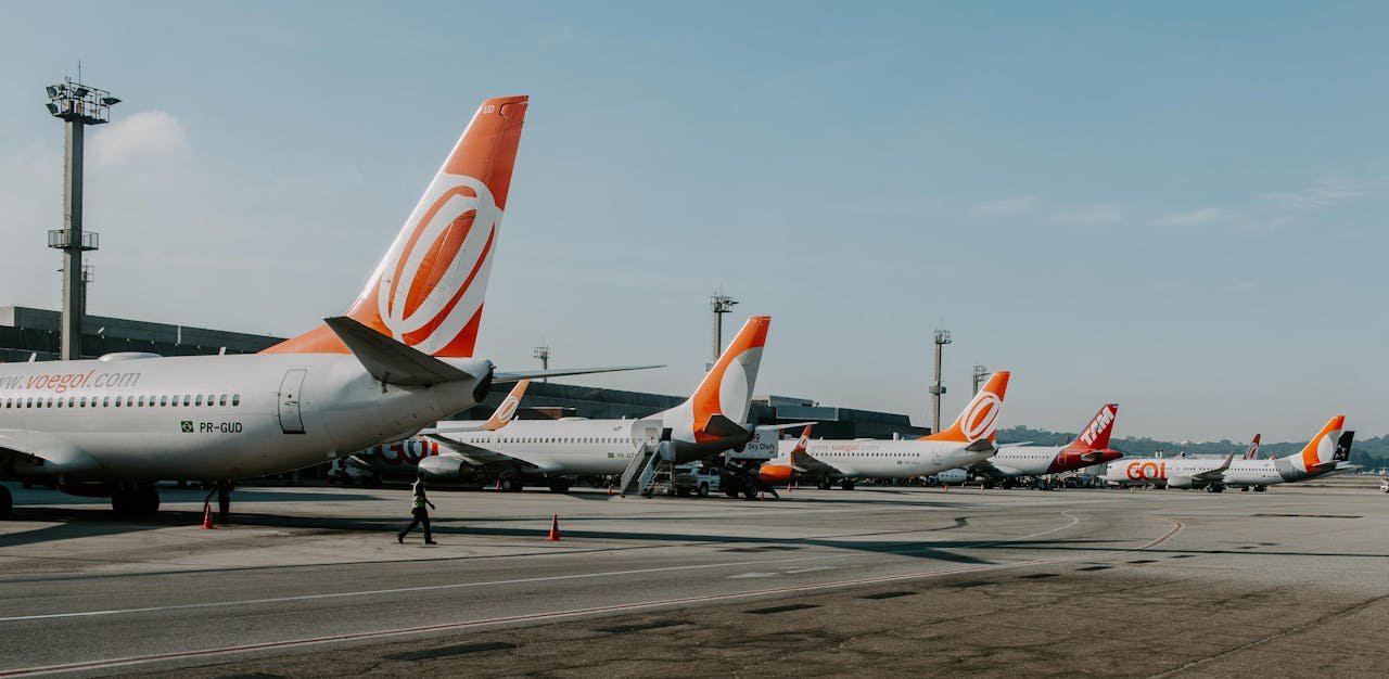 gallery-2 Multiple airplanes on tarmac at a busy airport during daytime, showcasing aviation and travel.