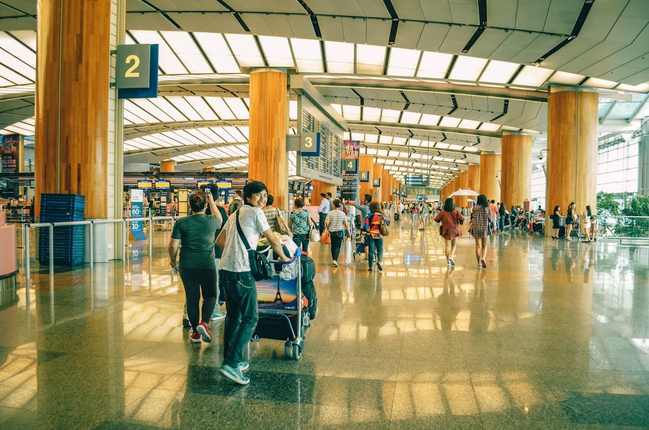 gallery-6 Travelers bustling through Singapore Changi Airport terminal, highlighting the dynamic and vibrant atmosphere of international travel.