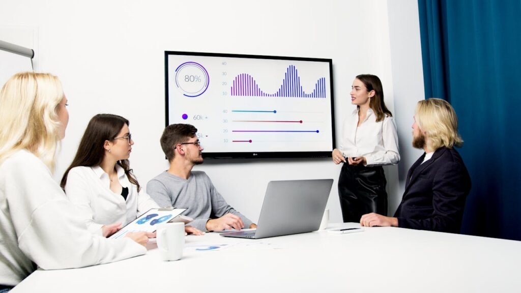 Professional business meeting with a team analyzing data on a presentation screen.